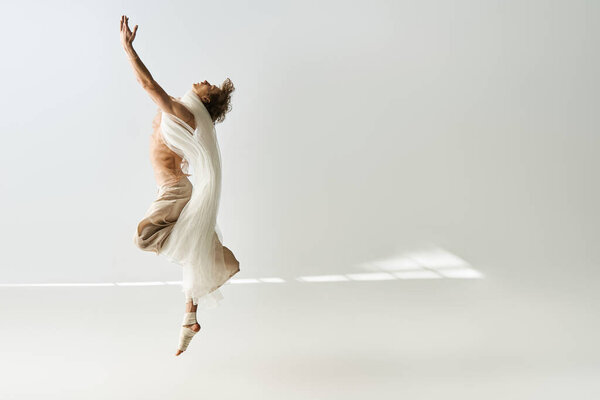 A young dancer with curly hair showcases his athleticism while dancing against a grey backdrop.