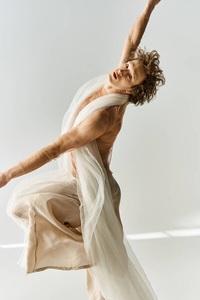 A young man dances gracefully in a studio, showcasing dynamic movements against a grey backdrop.
