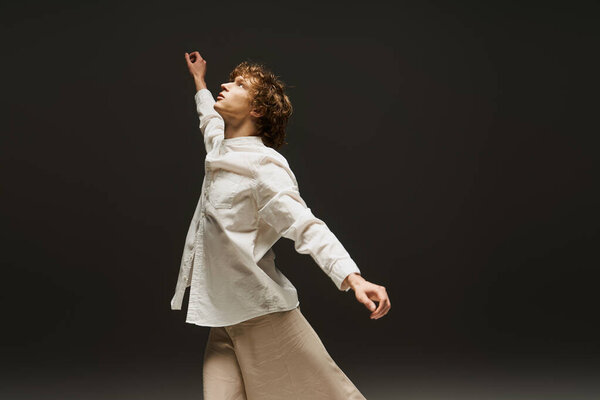 A young man with curly hair moves gracefully in a dance studio. He embodies joy and athleticism.