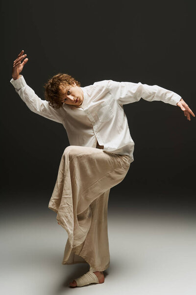 Молодой кудрявый танцор демонстрирует изящные движения в современном студийном пространстве..