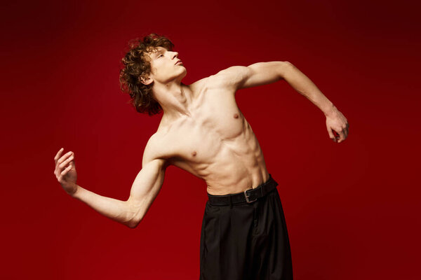 Curly-haired dancer performs passionately against a bold red background, showcasing his artistry.