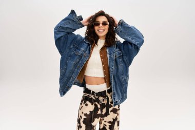 Genç bir kadın, bir stüdyoda ineklerin baskılı pantolonlarını giyerek, modaya uygun bir şekilde poz veriyor..