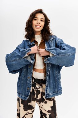 Tarz sahibi genç bir kadın modaya uygun inek desenli pantolon ve kot ceketle rahatça poz veriyor..