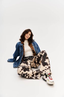 Şık bir kadın, kendine güvenen bir şekilde inek desenli pantolonla poz verir, stüdyoda moda yayar..