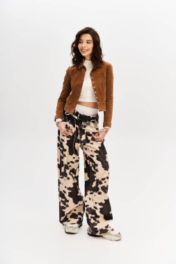 Genç bir kadın moda anlayışını gösteriyor. İnek desenli pantolon ve stüdyo ortamında şık bir bluz..