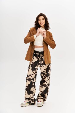 Parlak stüdyo ayarı, göz alıcı inek desenli pantolonu olan modaya uygun giyinmiş genç bir kadın içeriyor.