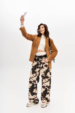 Moda kıyafetli genç bir kadın şık bir stüdyo ortamında selfie çekmekten hoşlanıyor..