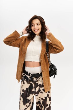 Modaya uygun genç bir kadın, modaya uygun inek desenli pantolonlar ve şık bir spor ceketle rahatça poz veriyor..