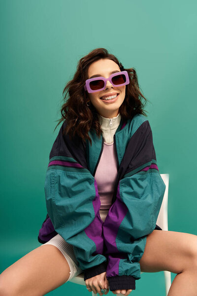 A young stylish woman with sunglasses showcases sporty fashion in a vibrant studio setting.