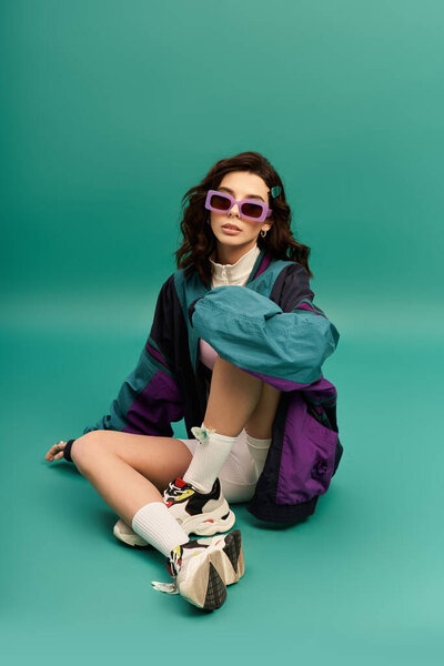 A young woman showcases her trendy sporty outfit in a vibrant studio setting.