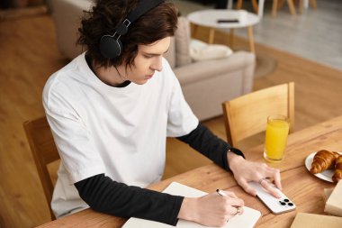 Sıcak ve davetkar bir atmosferde, rahat giyinmiş genç bir adam içki içerken notlar yazar..