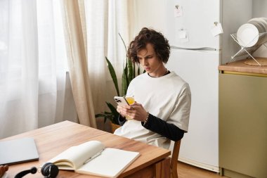 Genç bir adam rahat bir ortamda akıllı telefonuyla evde rahatlar..