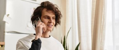 Şık bir genç adam evinde oturmuş, telefonda rahatça sohbet ediyor..