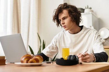 Genç bir adam evinde dizüstü bilgisayarı, abur cuburu ve içkisiyle oturup görevine odaklanmış..