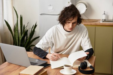 Genç bir adam evde çalışıyor, rahat giysiler içinde, sakin bir ortamda..