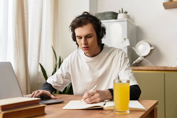 Young man diligently writes notes while listening to music in a cozy home environment.