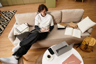 Genç adam evinde dizüstü bilgisayarını ve rahat giysilerini giyer..