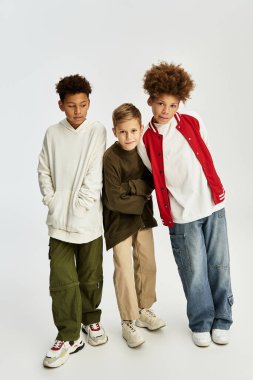 Three little boys in stylish outfits pose happily together, showcasing their vibrant fashion sense.