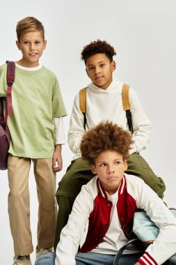 Three cute boys showcase friendship in stylish outfits in a trendy indoor space.