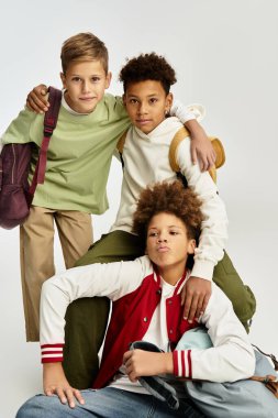 Three adorable boys in trendy outfits enjoy a fun moment, embracing friendship and togetherness.