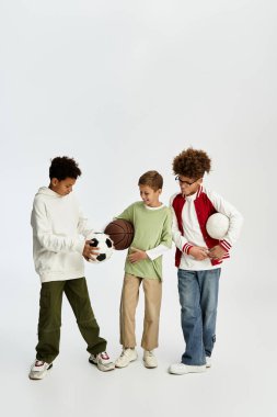 Three cheerful boys in colorful outfits bond over sports balls, showcasing their friendship.
