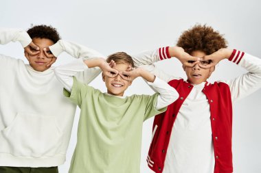 Three adorable boys dressed in vibrant attire come together, sharing laughter and fun.