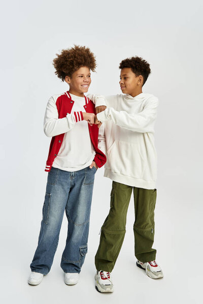 Два очаровательных молодых мальчика разделяют момент товарищества, одетые в модную одежду.