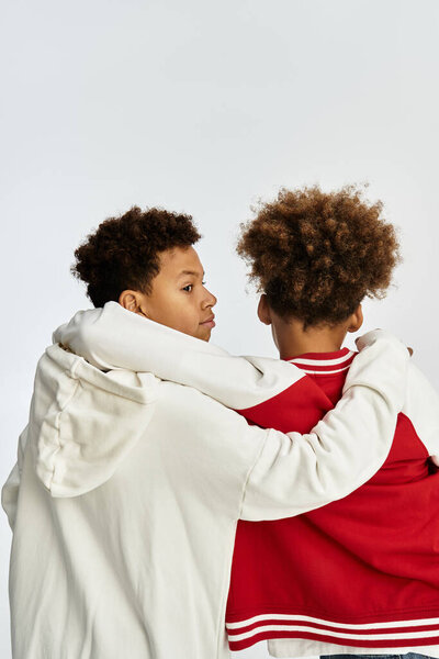 Два маленьких мальчика обнимают друг друга, демонстрируют свои стильные наряды и товарищество..