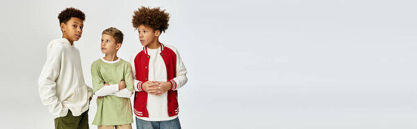 Три очаровательных маленьких мальчика стоят вместе в модных нарядах, излучая радость и товарищество.