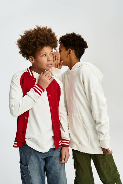 Two adorable boys in vibrant outfits share a secret moment full of laughter and togetherness.