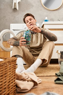 Dövmeli genç adam evde rahatlıyor, çamaşırları düzenliyor ve yaratıcı bir projeyle meşgul oluyor..