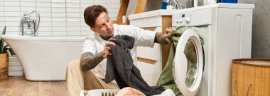 Dövmeli bir adam rahat bir banyoda çamaşırları yıkıyor ve rahat bir atmosfer yaratıyor..