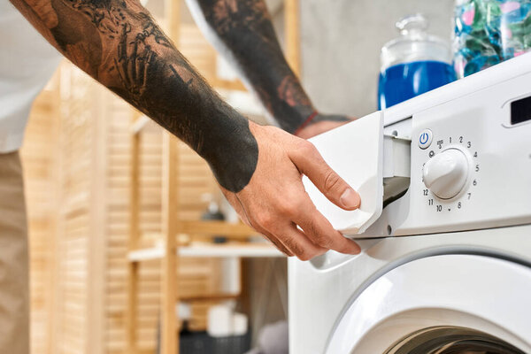 Comfortable young man engaged in daily chores at home, showcasing his tattoos in a relaxed setting.