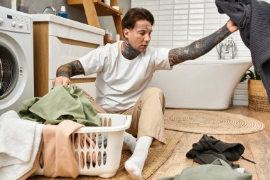 Yakışıklı genç adam, şık bir ev ortamında sıcak bir öğleden sonra çamaşırları yıkıyor..