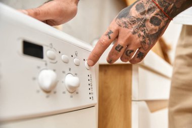 Dövmeleri olan genç bir adam evde rahatlıyor, çamaşırları düzenliyor..