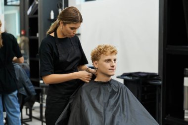 Modayı takip eden bir kuaför, müşterinin saçı üzerinde çalışır..