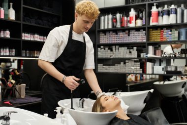 Yetenekli stilist, çağdaş güzellik salonu ortamındaki bir müşteriye ferahlatıcı bir yıkama sunuyor..