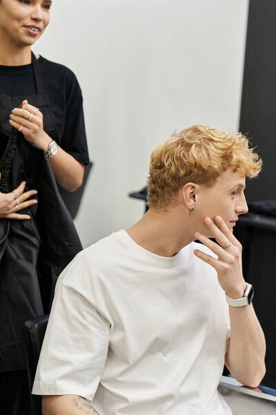 A stylist prepares for a trendy haircut while the client contemplates a new look in the salon.