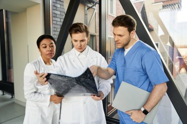 Three doctors review medical images together in a contemporary hospital setting.