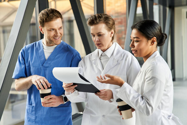 Three diverse healthcare professionals talk about medical documents in a modern hospital.