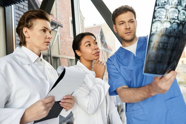 Three dedicated doctors engage in vital discussions while analyzing radiology results in a hospital.