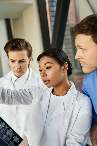 Three dedicated doctors discuss a patients medical scan in a contemporary hospital environment.