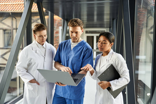 Three diverse doctors engage with technology in a contemporary healthcare setting.