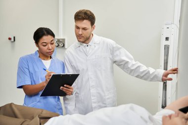 At a top facility, a doctor and nurse help a female patient prepare for her MRI scan.