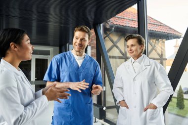 Three doctors engage in a lively discussion about patient care in a contemporary hospital.