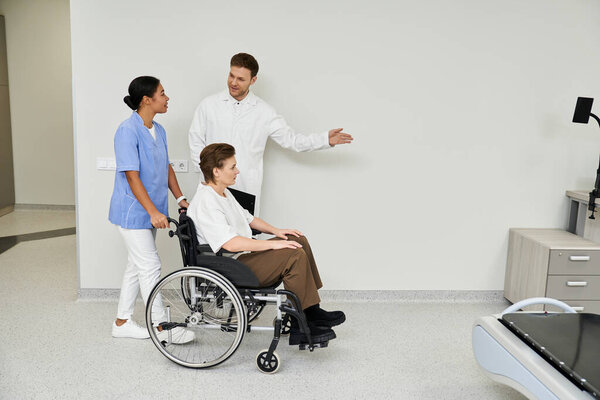 Handsome doctor and nurse assist a female patient in wheelchair near the MRI machine at hospital.