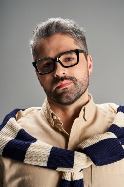 Gözlüklü şık bir adam modern bir stüdyoda zarafet sergiliyor..