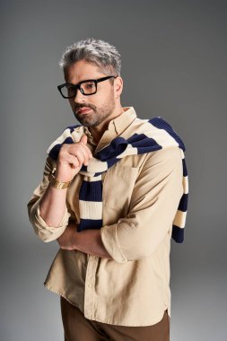 Gözlüklü yakışıklı adam şık bir elbise içinde zarif bir poz veriyor, sofistike ve çekici..