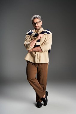 Gözlüklü modaya uygun bir adam şık bir kıyafet ve rahat bir tavırla poz verir..