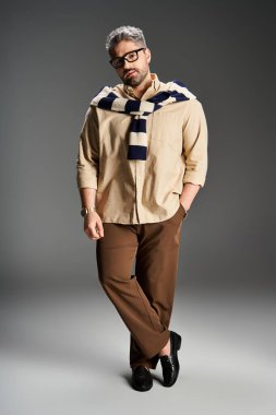 Kendine güvenen bir adam şık bir kıyafet içinde, gözlüklü, modern moda eğilimlerini somutlaştırıyor..